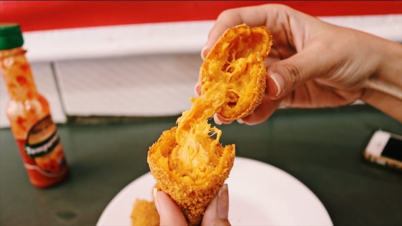 Coxinha de frango com catupiry da Esfiha & Cia, no bairro de Campinas, em Goiânia, dividida ao meio com a mãos